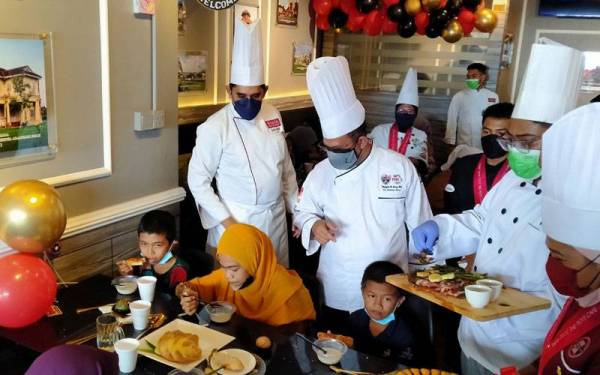 Shahrul Aman (berdiri, dua dari kiri) melayani asnaf yang hadir pada Program Chef Table 2022 Bersama Asnaf di The Pjoi's Cafe, di sini pada Sabtu.