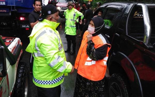 Siti Zailah (kanan) dan Mohd Nasaruddin (kiri) semasa melakukan tinjauan di Jalan Kalbok Lima, Rantau Panjang yang dinaiki air dan ditutup kepada kenderaan ringan pada Ahad.