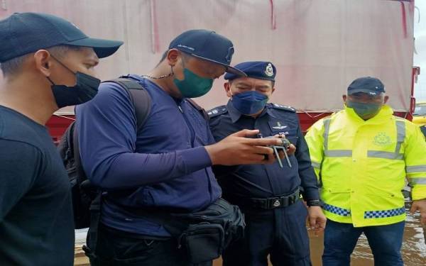 Muhammad Zaki (dua dari kanan) melakukan pemantauan menggunakan dron bagi melihat kawasan-kawasan yang sebelum ini tidak pernah ditenggelami banjir di Rantau Panjang pada Isnin.