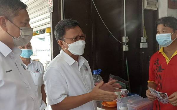 Mohd Shafie ( tengah) menyapa peniaga di Taman Utama sewaktu kempen calon Warisan di Pekan Nanas pada Isnin.