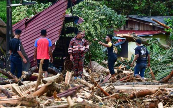 Anggota Jabatan Bomba dan Penyelamat Malaysia (JBPM) bersama penduduk kampung meninjau keadaan sebuah rumah yang dipenuhi timbunan kayu dipercayai dihanyutkan bersama kepala air akibat hujan lebat semasa tinjauan di Kampung Belukar Bukit, pada Isnin. - Foto Bernama