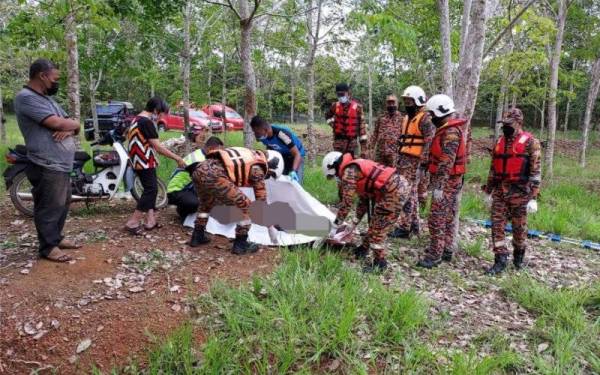 Anggota bomba mengangkat mayat warga emas yang lemas di dalam kolam ikan miliknya di Jalan Kelompang, Kampung Kenawar, Pogoh, Segamat, pada Selasa.