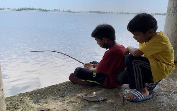 Mohd Al Hakim (kanan) dan Nik Mohd Shahmi asyik memancing ketika ditemui pada jam 11 pagi Selasa.