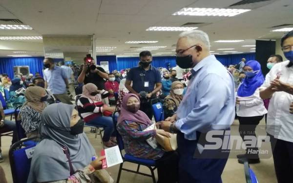 Noh (kanan) menyampaikan bantuan BBKM kepada salah seorang usahawan terjejas banjir di Selangor pada Disember lalu.