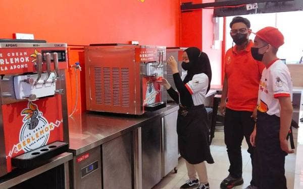 Ahmad Firdaus bersama dua pekerja di kedai Ice Cream Berlemok Gula Apong cawangan Jalan Bukit Ubi di sini.
