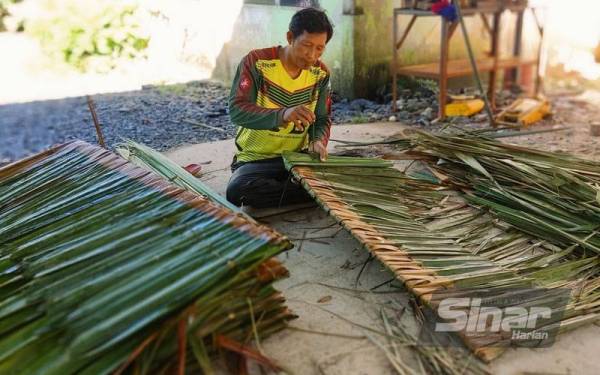 Mat Isa menjahit atap rumbia menggunakan kulit pokok bembam di rumahnya di Kampung Tebing, Napoh pada Rabu.