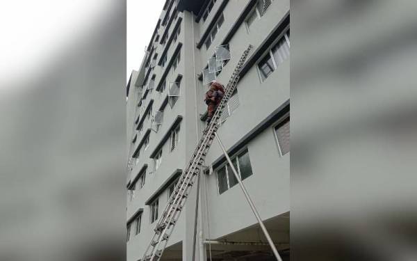 Anggota bomba membantu membawa turun kanak-kanak perempuan yang terperangkap di luar tingkap rumah di tingkat tiga sebuah pangsapuri pada Jumaat. - Foto JBPM Pahang