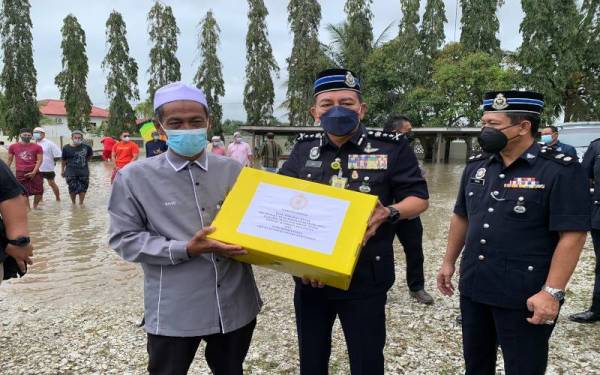 Muhammad Zaki (tengah) menyampaikan sumbangan kepada penduduk di Kampung Simpangan Hilir, pada Jumaat. 