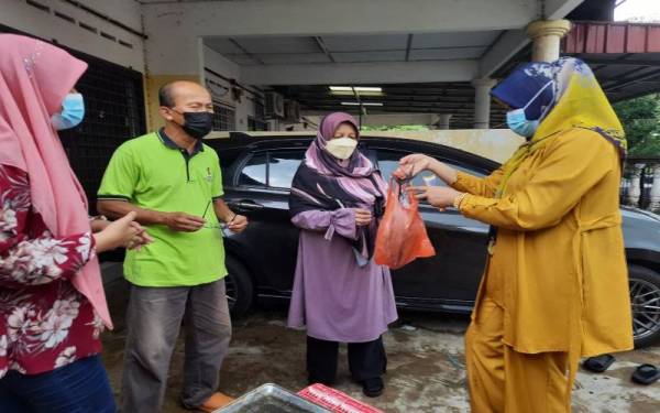 Tengku Susilawati (kanan) menjual ikan kepada salah seorang pelanggan.