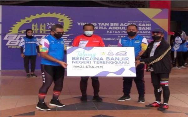 Zaini (dua dari kanan) menyaksikan penyerahan replika cek sumbangan lebih RM21,000 untuk Tabung Bencana Banjir Negeri Terengganu oleh Mohd Rohaimi (kanan) kepada Tengku Farouk selepas selesai kayuhan Program Bridge to Bridge: Charity Ride Kontinjen Terengganu yang diadakan di Dataran Pantai Batu Burok, pada Sabtu.