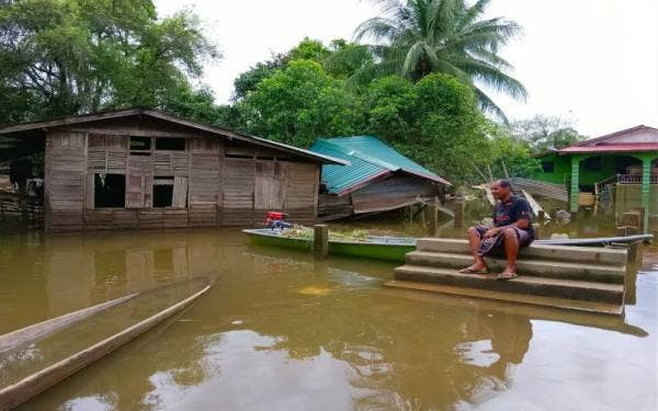 Mohd Rozi hanya mampu duduk di atas tangga yang masih lagi kekal ada selepas rumahnya dihanyutkan arus banjir pada Ahad.
