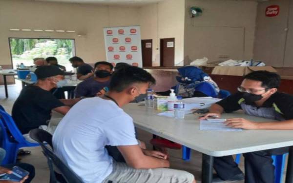 Petugas kesihatan Klinik Siti memberi penerangan kepada pekerja ladang Sime Darby sebelum menerima suntikan imunisasi.