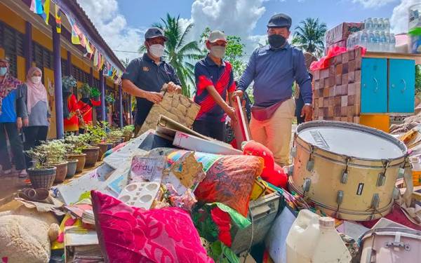 Hashim Alang (kanan) bersama kakitangan Kemas menunjukkan sebahagian daripada barangan pembelajaran yang rosak akibat banjir di Tabika Kemas di Kompleks Unit Pencegah Penyeludupan (UPP) Rantau Panjang pada Isnin.