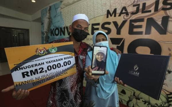 Abd Razak dan Najah Aspalila memegang gambar Allahyarhamah Hanis Nuraishah Nasuha bersama diploma dan Anugerah Yayasan Risda yang diterima