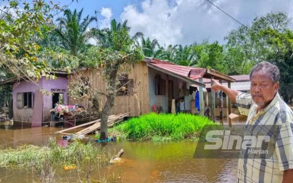 Abdul Majid menunjukkan keadaan terkini rumahnya dipenuhi rumput yang dihanyutkan banjir di Kampung Bendang Perol, Rantau Panjang pada Isnin.