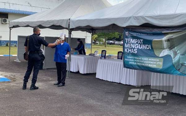 Petugas KKM membuat pemantauan terhadap anggota yang didapati bergejala di tempat mengundi khas yang disediakan di luar dewan mengundi, di sini, pada Selasa.