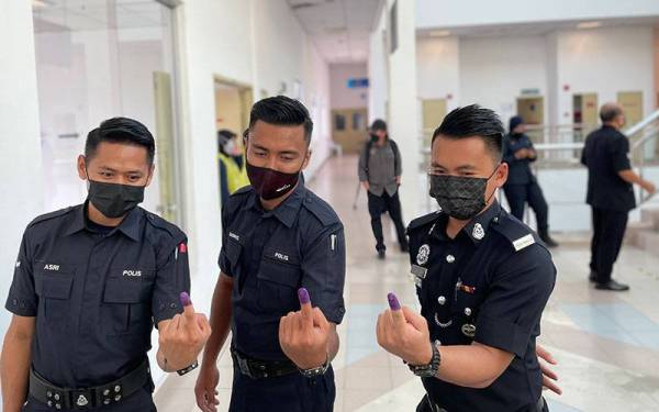 Tiga anggota polis menunjukkan jari mereka selepas selesai membuang undi awal di IPD Batu Pahat.