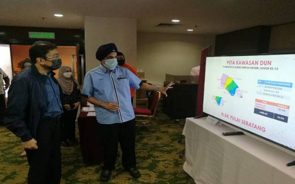 Zahidi (kiri) mendengar penerangan dan taklimat ringkas semasa lawatan ke Pusat Media Pilihan Raya Umum Dewan Undangan Negeri (DUN) di sebuah hotel di Johor Bahru, pada Selasa.