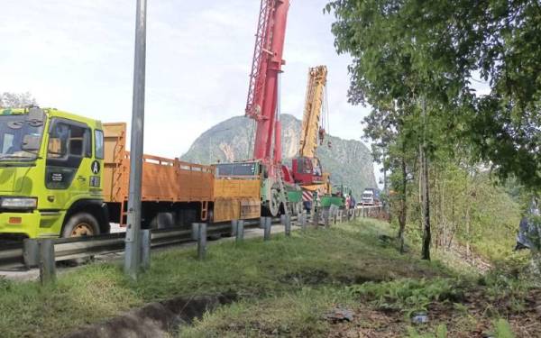 Dua kren digunakan untuk mengalih lori kontena yang menghalang jalan masuk ke Kampung Sungai Peria, Sahom, di sini, pada Selasa.