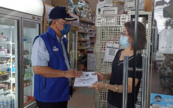 Hasni (kiri) menyantuni peniaga di sekitar Pekan Benut pada Selasa.