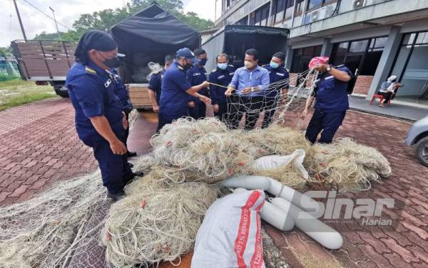 Ruzaidi ( tiga dari kanan) memeriksa pukat pari yang dirampas di Jabatan Perikanan Terengganu, pada Rabu.