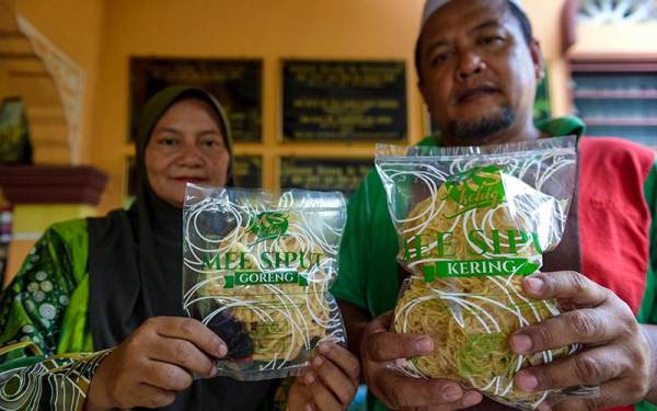 Md Shahir (kanan) bersama isteri menunjukkan dua jenis mi iaitu mi siput goreng dan mi siput kering berserta sambal tumis ketika tinjauan pembuatan makanan tradisional tersebut di rumahnya di Kampung Sawah Ring, Tangkak. - Foto Bernama