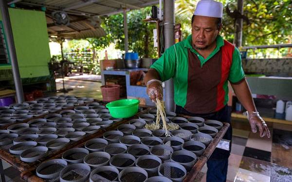 Md Shahir menunjukkan proses membentuk mi siput yang telah dimasak sebelum dikeringkan ketika tinjauan pembuatan makanan tradisional tersebut di rumahnya di Kampung Sawah Ring, Tangkak. - Foto Bernama