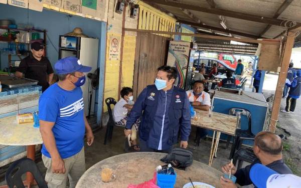 Azalina (berdiri, kanan) ketika menyantuni nelayan, di Pengerang pada Jumaat.