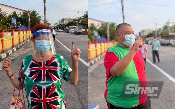 Sui Veck (kiri) dan Azman Ali menunjukkan jari mereka selepas mengundi di SMK Sri Muar.