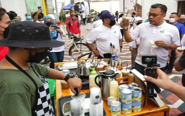 Mohd Sharkar (kanan) mencuba kelazatan kopi tempatan yang dijual di gerai kopi yang dibuka di kawasan Kuantan Art Street sempena Majlis Pelancaran Kuantan Car Free- Green Hour 2022 di sini pada Ahad.