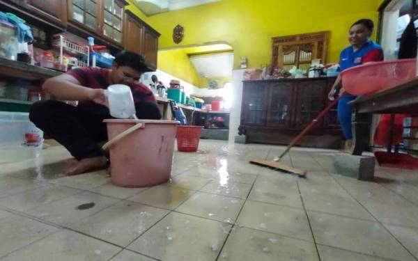 Dua anak Haraya membersihkan kesan banjir kilat selepas hampir seminggu meninggalkan rumah.