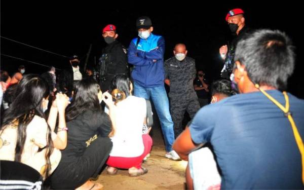 Khairul Dzaimee ketika membuat pemeriksaan dokumen terhadap individu yang ditahan dalam operasi di penempatan setinggan di pinggir Sungai Likas, Kota Kinabalu.