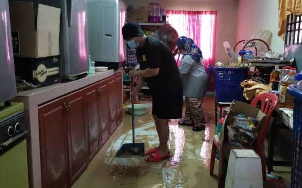 Mohd Faizal bersama isterinya, Nurul Artikah Haironi, 32, memgemas rumah mereka yang dipenuhi selut akibat banjir di Desa Seri Chepor, Chemor