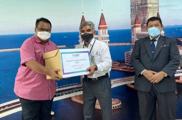 Idris (tengah) menyampaikan sumbangan keperluan sekolah kepada Guru Besar SK Darat Batu Rakit, Mohd Johari Jusoh (kiri).