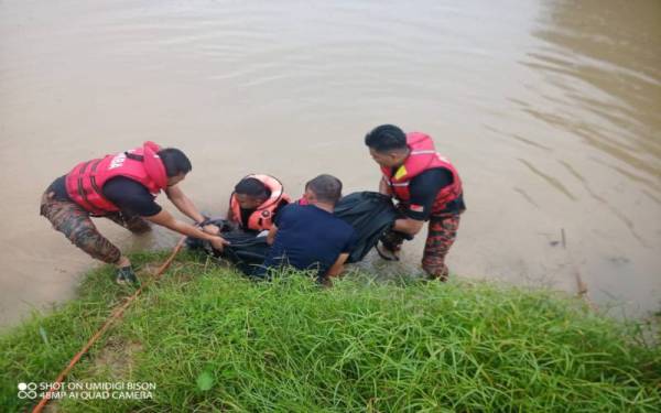 Anggota bomba mengangkat mayat seorang remaja lelaki yang lemas di Sungai Kapeh, Segamat pada Selasa.