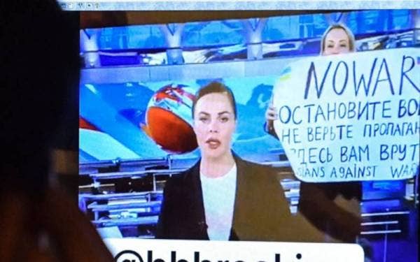 Imej menunjukkan seorang editor, Marina Ovsyannikova (berdiri di belakang pembaca berita) memegang plakad bagi menentang perang Ukraine di Rusia pada Isnin lalu. - Foto AFP