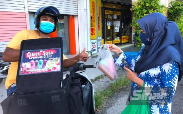 Nik Muhamad Afiq menjual susu berperisa kepada seorang pelanggan, Rosliza Mohamed di Kota Bharu.