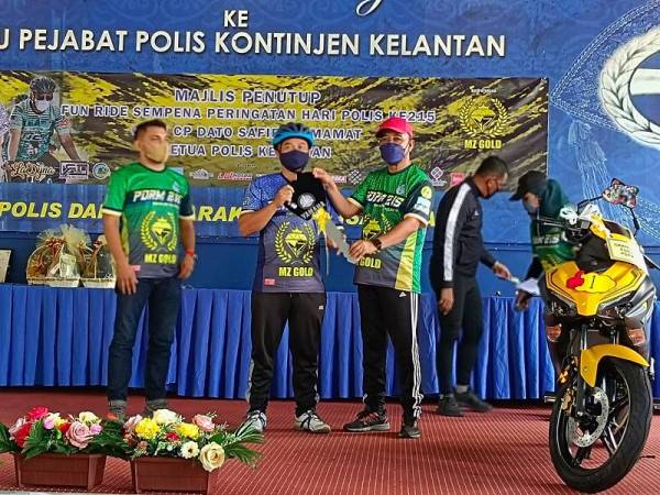 Shafien (kanan) menyampaikan hadiah utama cabutan bertuah berupa sebuah motosikal kepada penerima semasa program kayuhan basikal amal sempena Sambutan Hari Polis Ke-215 di Ibu Pejabat Polis Kontinjen (IPK) Kelantan, Kota Bharu pada Sabtu.