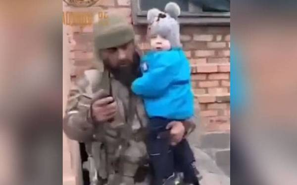 Seorang askar Chechnya mendukung seorang kanak-kanak keluar dari sebuah bangunan apartmen di Mariupol, Ukraine baru-baru ini. - Foto Agensi