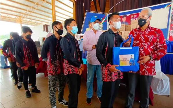 Annuar (kanan) menyampaikan sumbangan kepada pelajar tingkatan enam dari Parlimen Ketereh sempena program 'Back To School' di Yayasan Kemiskinan Kelantan (YKK), Kota Bharu, pada Ahad.