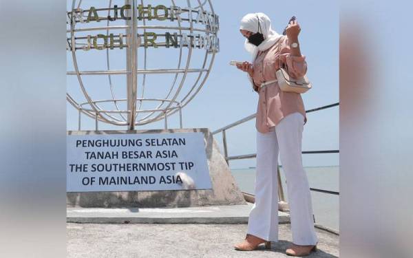 Pengunjung Fatin Humairah Mohd Sabri merakam detik gambar bayangnya semakin mengecil ketika fenomena tanpa bayang di Taman Negara Johor Tanjung Piai pada Khamis.
