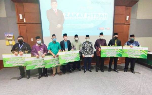 Ahmad Hairi (empat, kanan) dan Dr Asmadi (lima, kiri) menyempurnakan bantuan tahunan hari raya kepada wakil penerima selepas sidang akhbar pengumuman kadar zakat fitrah Pahang 2022 di Pejabat Muip, pada Khamis.