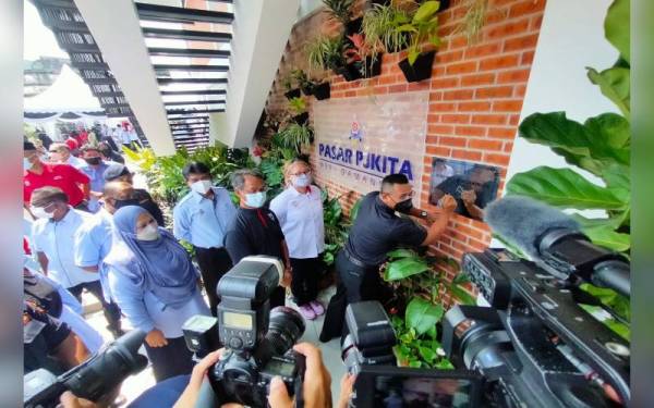 Amirudin (kanan) menandatangi plak pada Majlis Perasmian Pasar PJKITA @ Sri Damansara pada Jumaat.