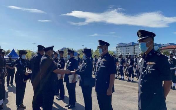 Idris menyampaikan sijil penghargaan kepada anggota dan pegawai polis sempena sambutan Hari Polis di dataran kawad, IPK Sabah, Kota Kinabalu.