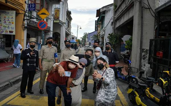 Kebanyakan pelancong teruja dengan kehadiran anggota polis yang memperagakan pakaian seragam lama sempena sambutan Hari Polis ke-215. Foto: Bernama