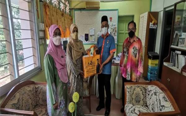 Bakri Sawir (kiri dari kiri) menyerahkan sumbangan kit ujian kendiri dan pelitup muka kepada pihak pengurusan sekolah berkenaan.