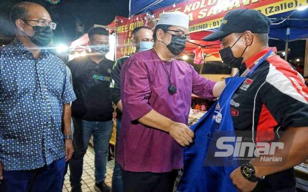 Sulaiman (dua,kiri) menyampaikan apron kepada salah seorang peniaga di Ley Park Station Dataran Ayer Keroh.