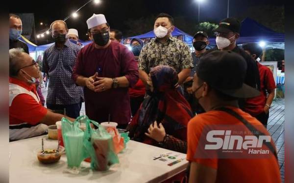 Sulaiman (dua,kiri) ketika menyantuni pengunjung di Ley Park Station Dataran Ayer Keroh, di sini, pada malam Ahad.