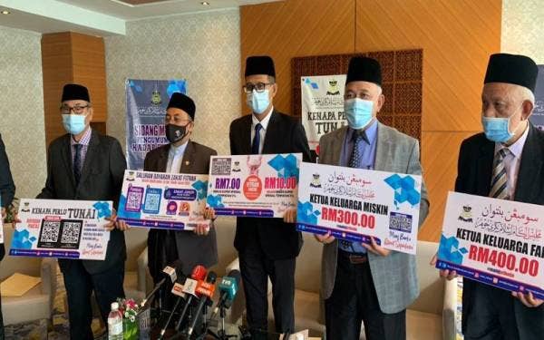 Mohd Fared (tengah) menunjukkan papan kenyataan jumlah kadar bayaran zakat fitrah yang ditetapkan pada sidang media berkenaan