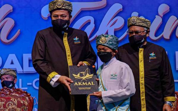 Hussin (kanan) mengiringi Ahmad Samsuri ketika menyampaikan anugerah kepada pelajar yang telah menamatkan hafazan 30 juzuk al-Quran sempena Majlis Haflah Takrimi Akmal 3.0 di Stadium Tertutup Gong Badak di Kuala Nerus.
